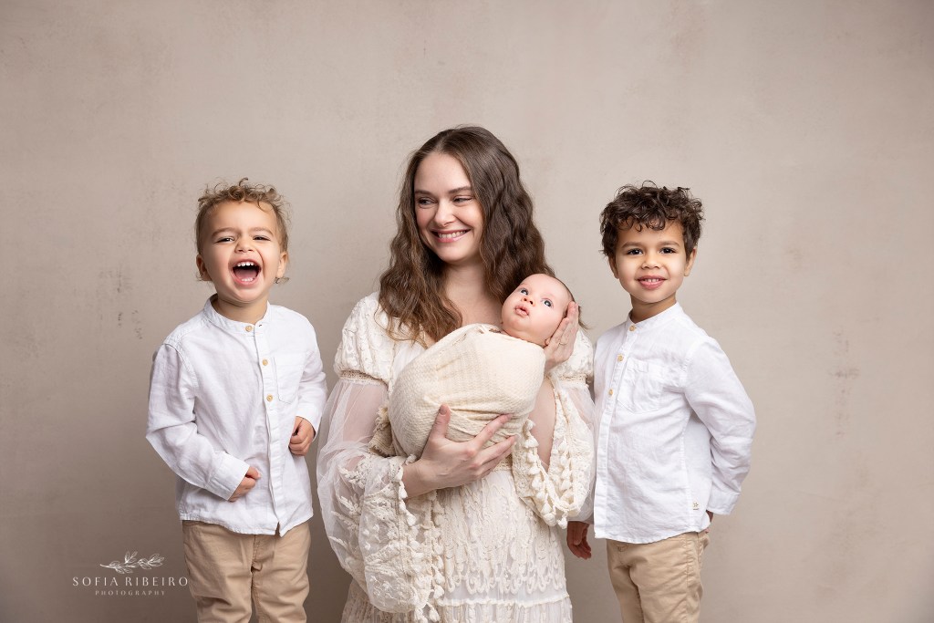 mom smiles at her sons during a posed family portrait for newborn photos in nj