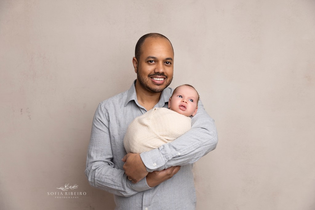 dad shares a smile while snuggling with his new baby boy during a photo session