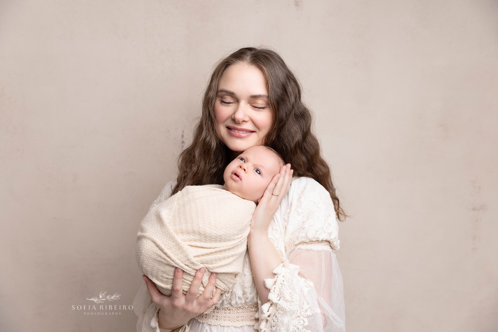 a new mom snuggles her baby boy wrapped in a cream wrap during a nj newborn session