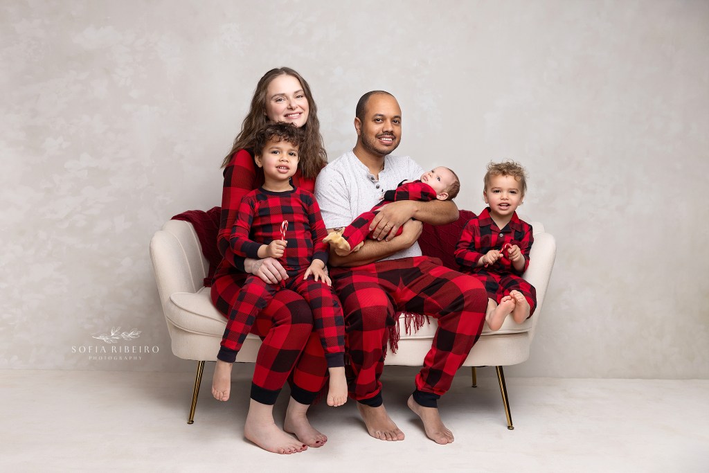 a family portrait in christmas plaid pajamas with their newborn baby