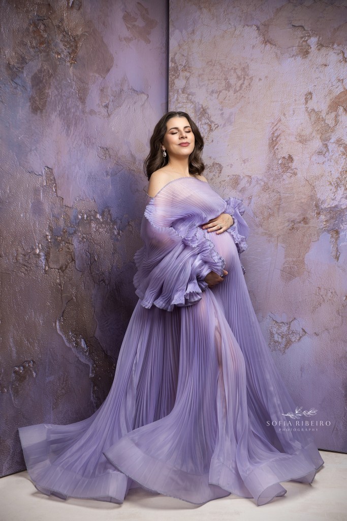 mom to be glows in a pleated lavender gown showcasing her baby bump during maternity photography in nj