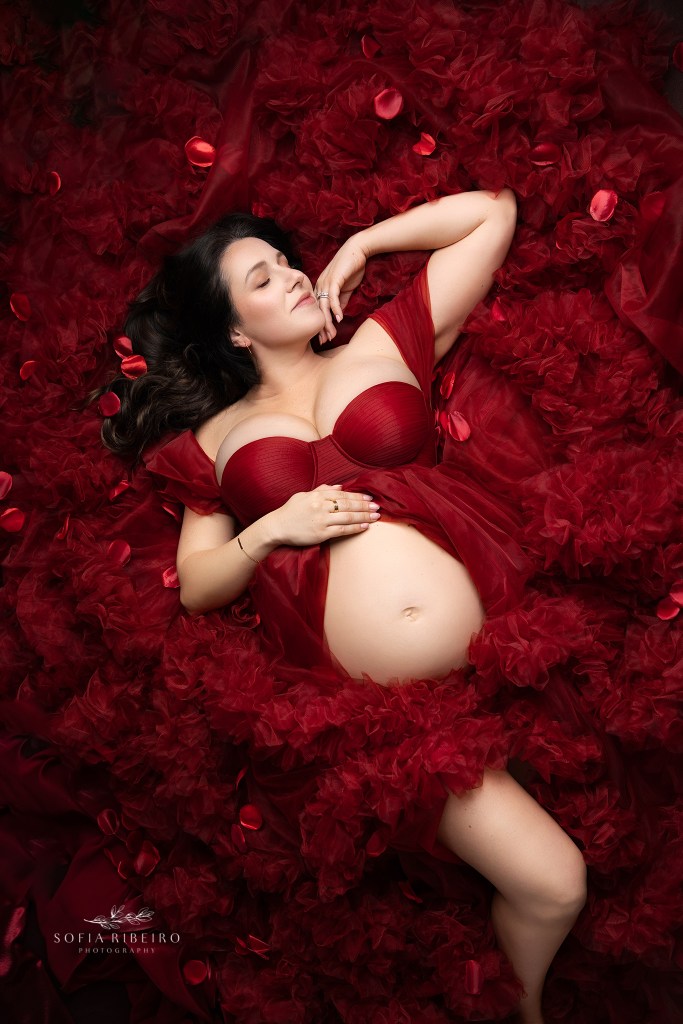 nj maternity photographer captures a valentine's day image of expectant mom in red dress and petals