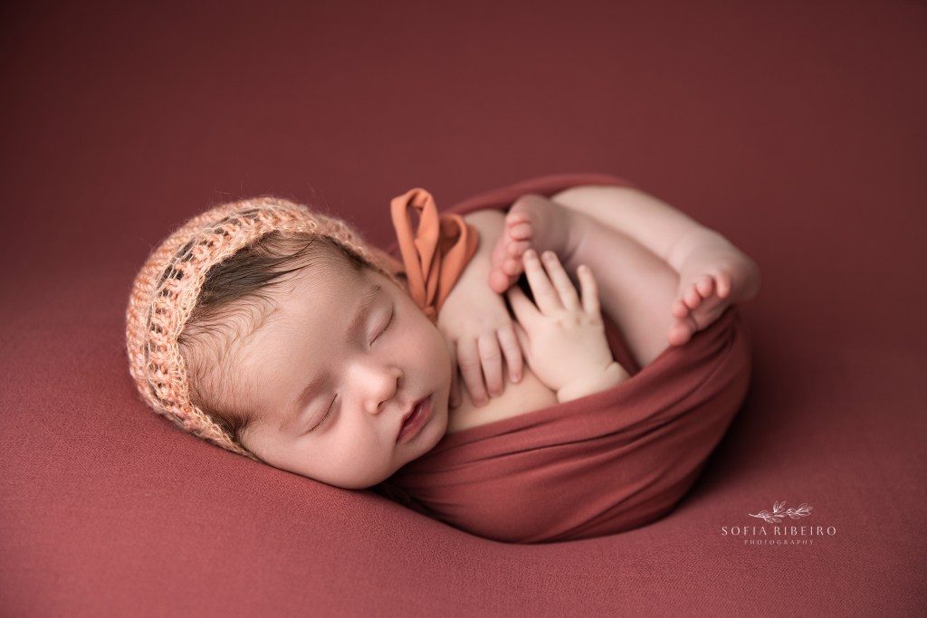 baby girl is wrapped in dusty pink for newborn photos