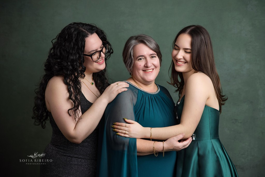 mom shares a smile with both daughters during her family portraits