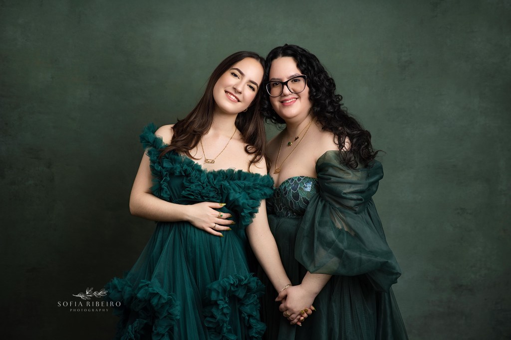 two sisters pose together during portraits for a family session in nj in matching green gowns