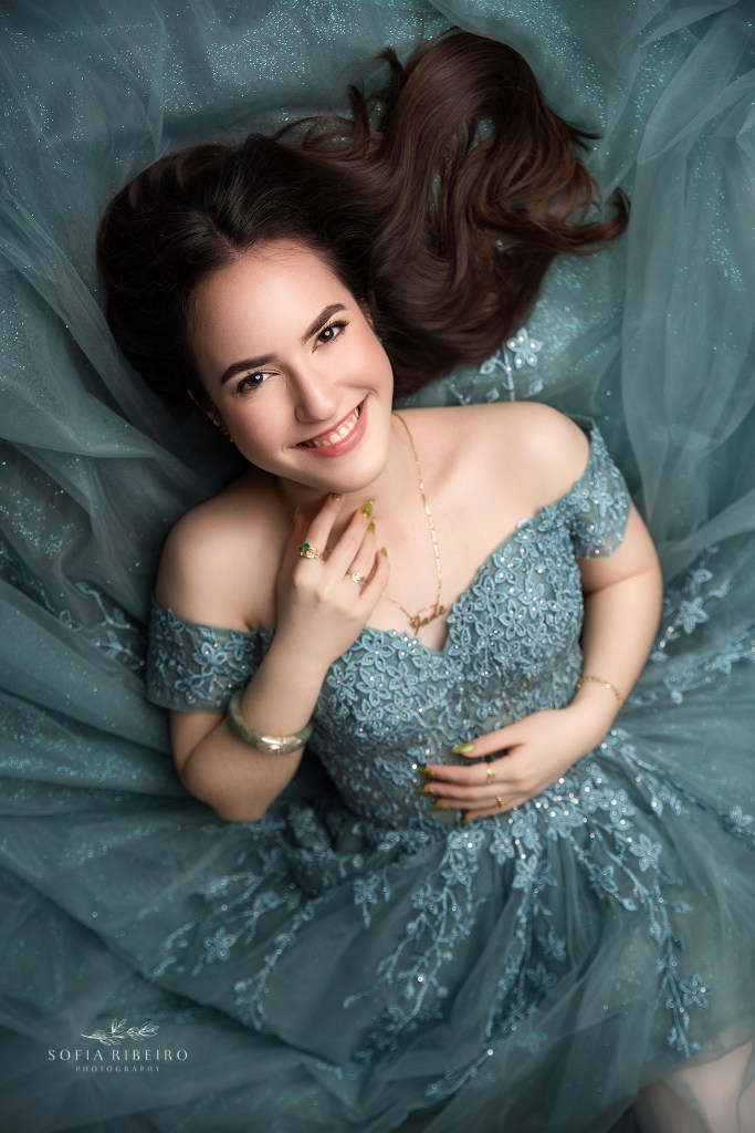 a lie down pose for sweet sixteen photos highlighting her sparkling gown