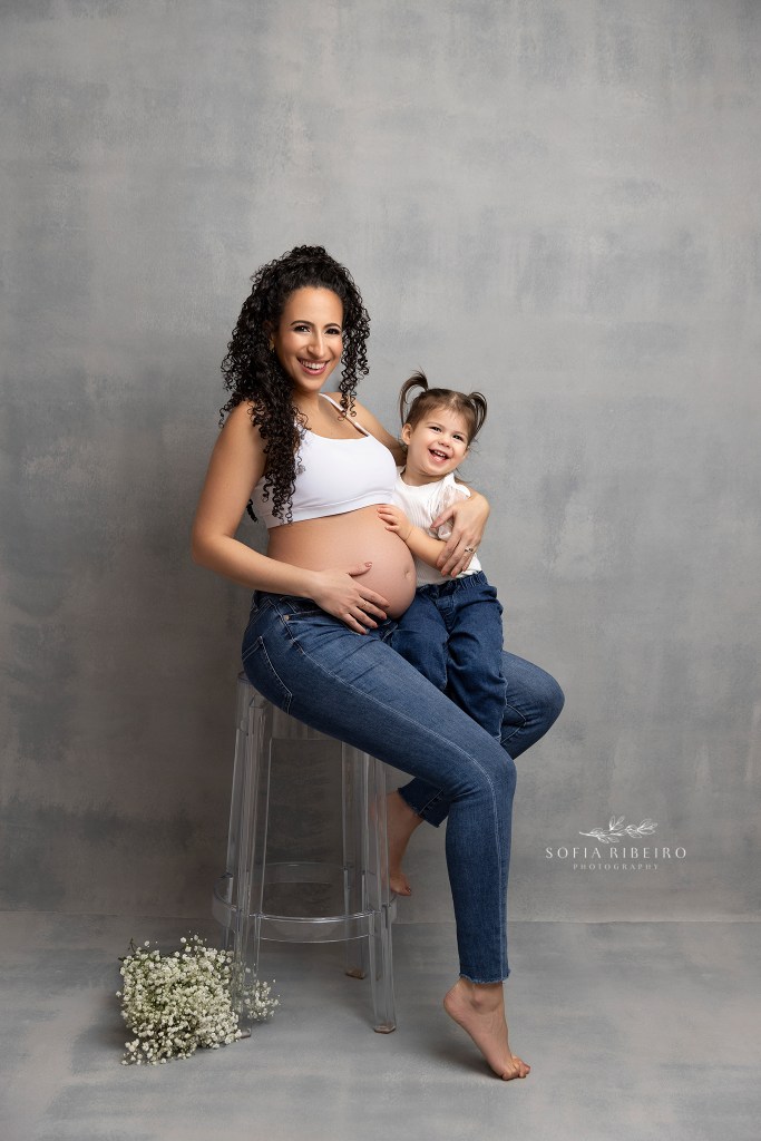 mom and her daughter cradled the baby bump in matching jeans and white tops