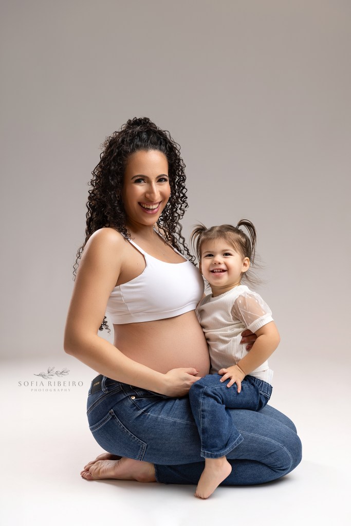 mom and her daughter cradled the baby bump in matching jeans and white tops
