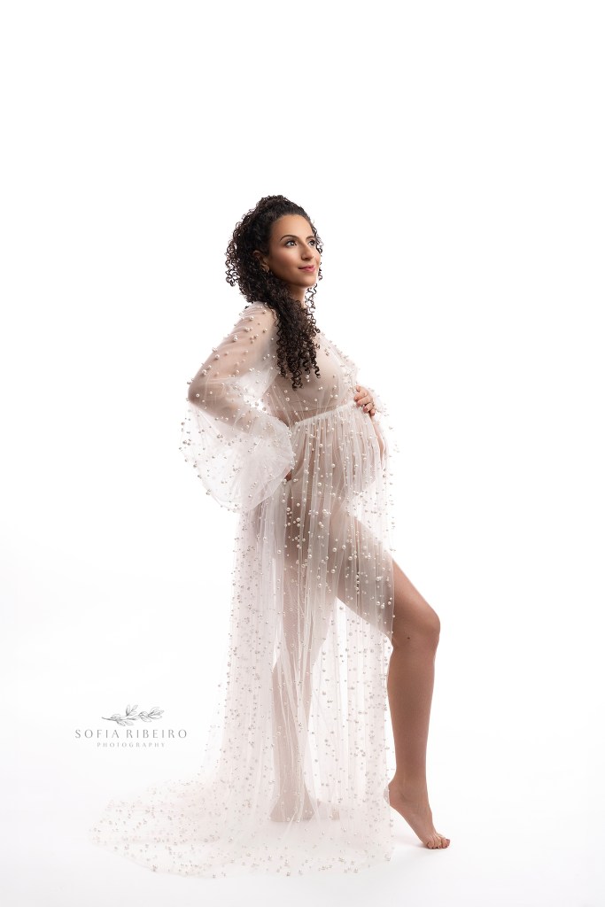 nj maternity photographer captures mom against a white backdrop silhouetted in a pearl sheer gown