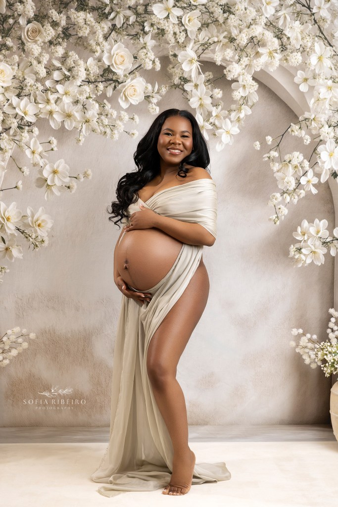 a glowing baby bump against a white floral backdrop