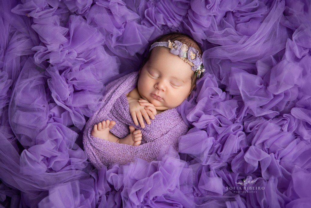 newborn baby girl swaddled in purple and layered in tulle