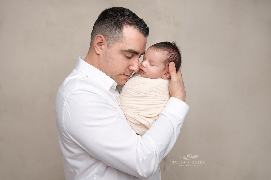 dad holds his new baby close for a newborn photo