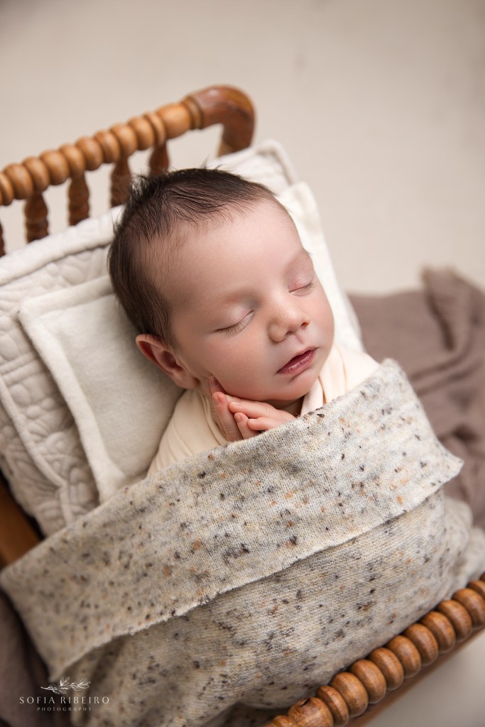 baby boy is posed in a bed prop in a neutral color scheme