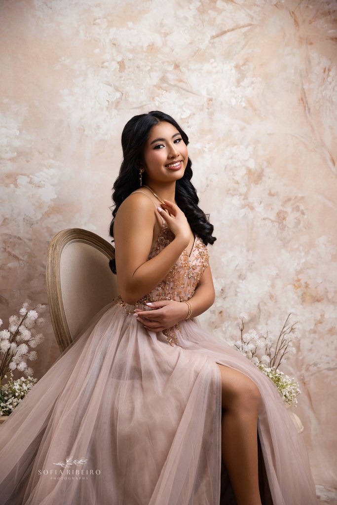 an elegant portrait of a sixteen year old against soft florals and peachy tones