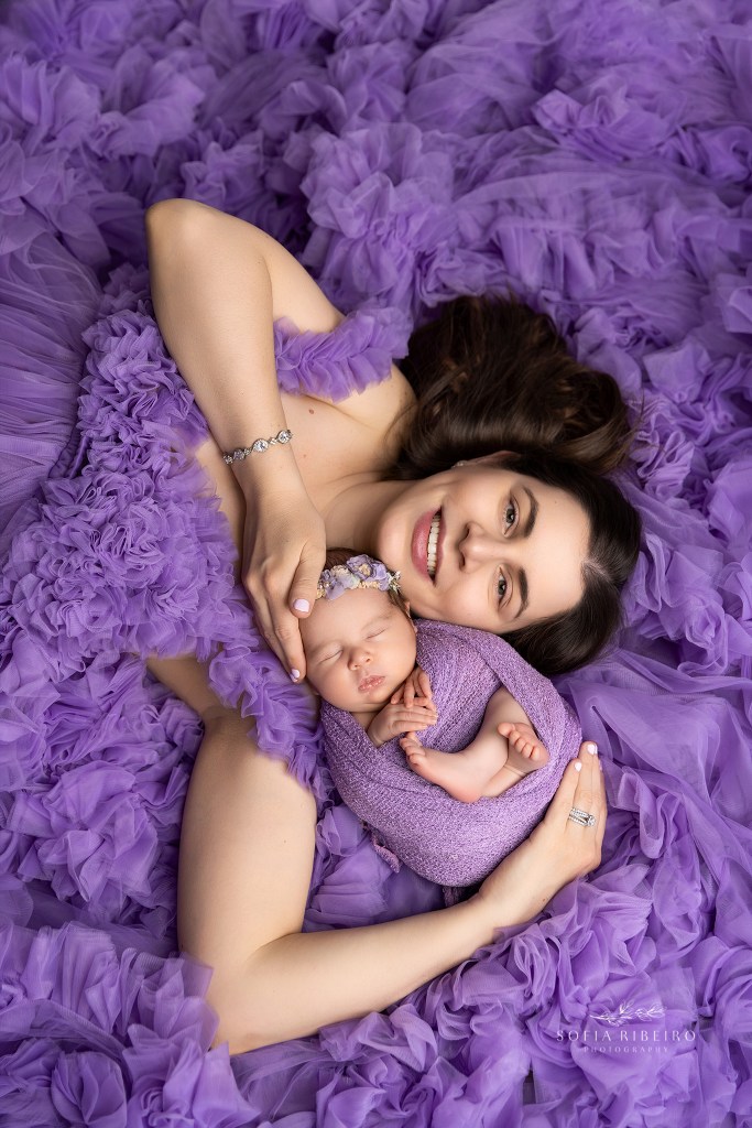 mom snuggles her new baby daughter in a bed of tulle