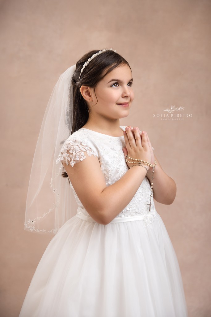 first holy communion photography in nj, a closeup of a girl against a pink backdrop
