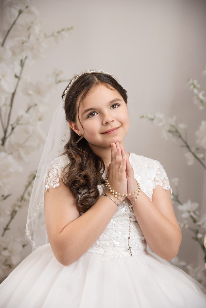 new jersey communion photographer captures a young girl against a white floral backdrop