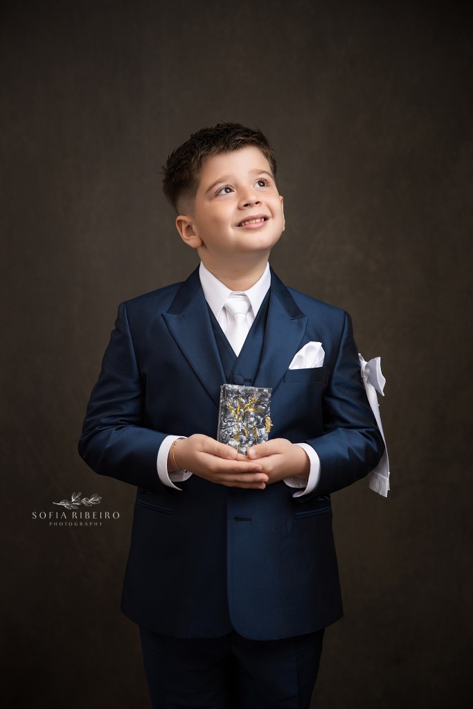 communion portrait of boy in navy suit against a brown backdrop