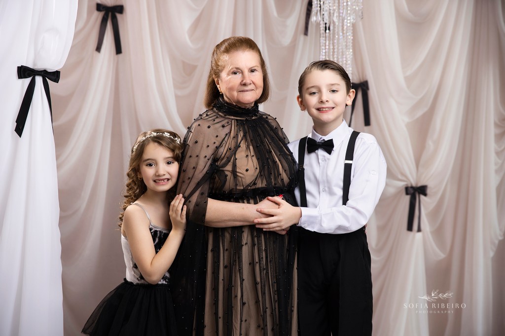 a portrait of grandma and her grandchildren in matching black tie outfits for a three generation photo session in nj
