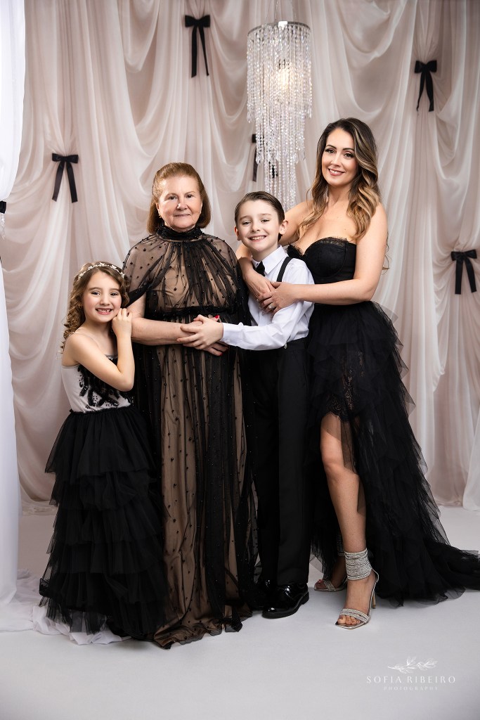 three generations in a portrait with mom grandma and her grandchildren set against a black and white refined backdrop