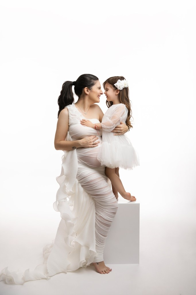 mom and daughter share a snuggle together for a maternity portrait