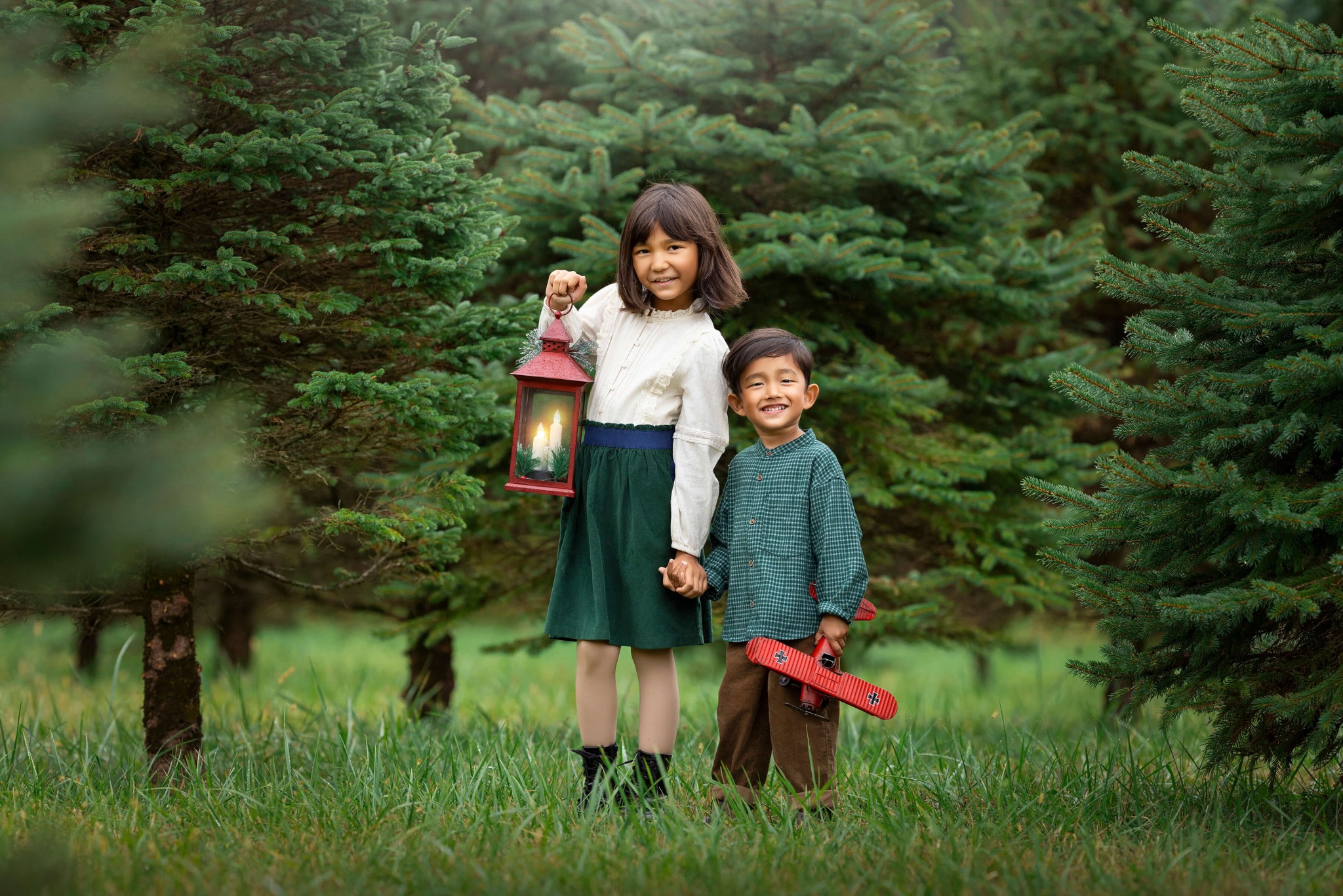 A young girl holds a lantern and hands with her younger brother in a christmas tree farm after finding preschools in summit nj