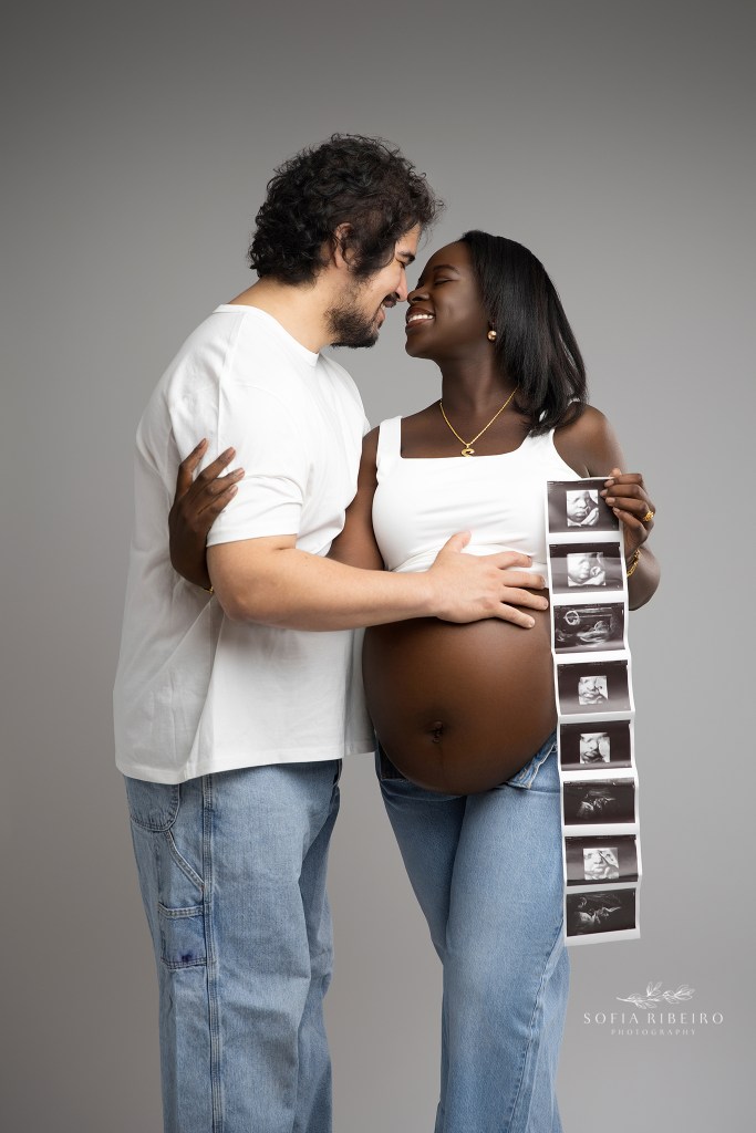 mom and dad share a snuggle together in matching denim looks for maternity photos with sonogram for an nj maternity photographer