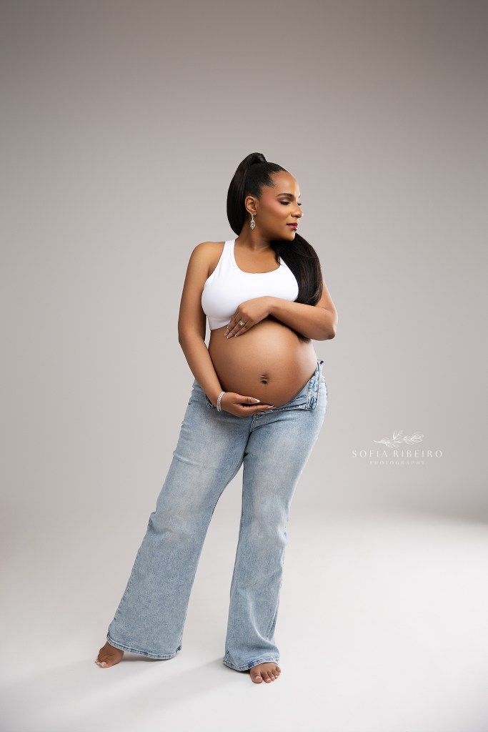 mom shines in a simple jeans and crop top look exposing her pregnant belly in a nj maternity photographer's studio