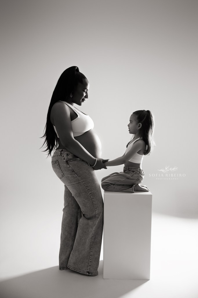 a black and white portrait between mom and daughter, holding her baby bump