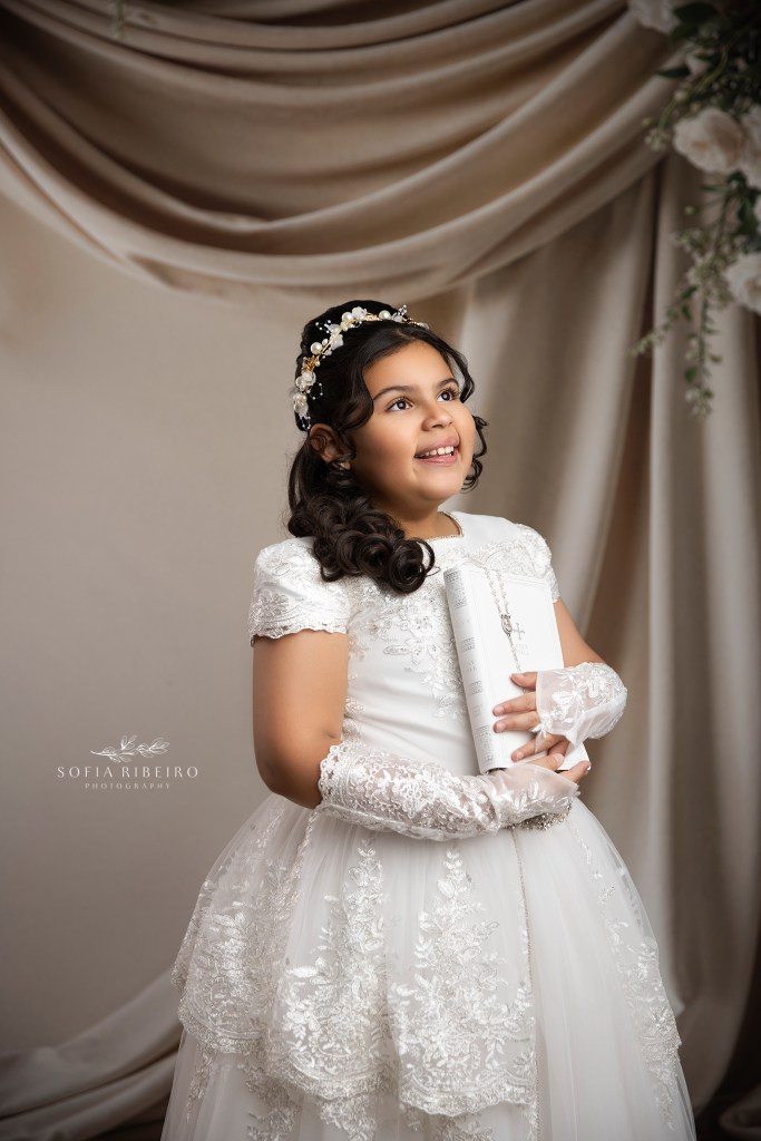 nj communino photographer captures a young girl holding a bible against a draped backdrop