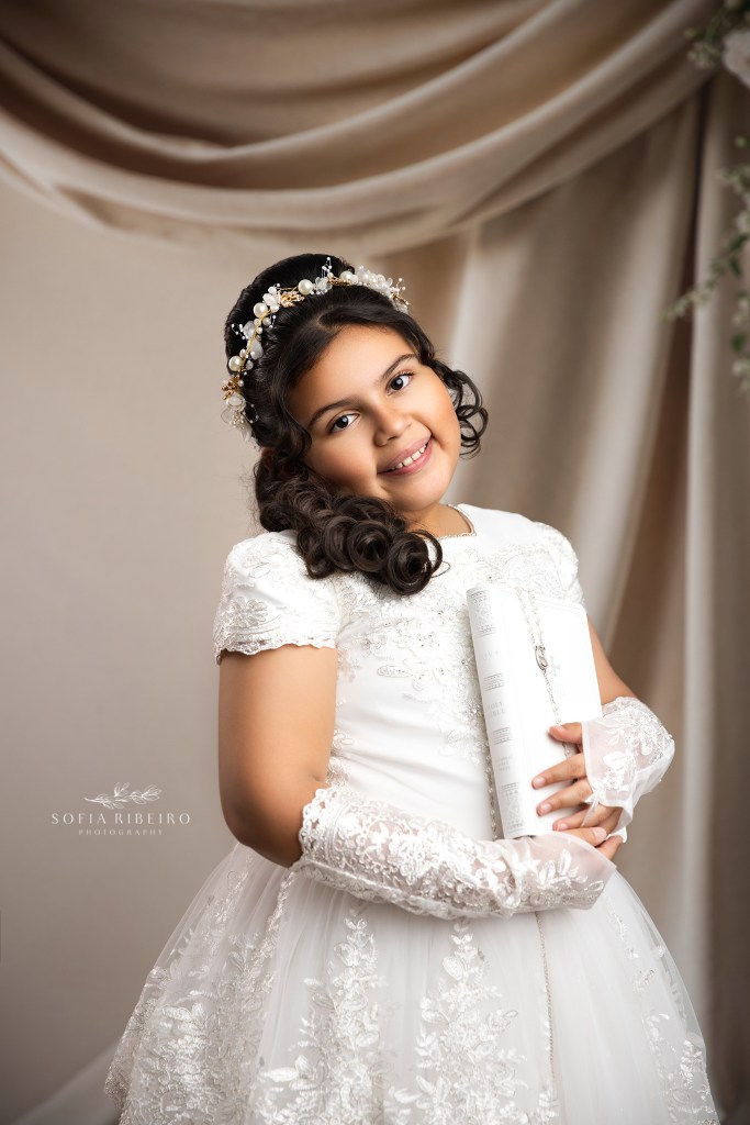 a first communion portrait of a young girl against a draped backdrop