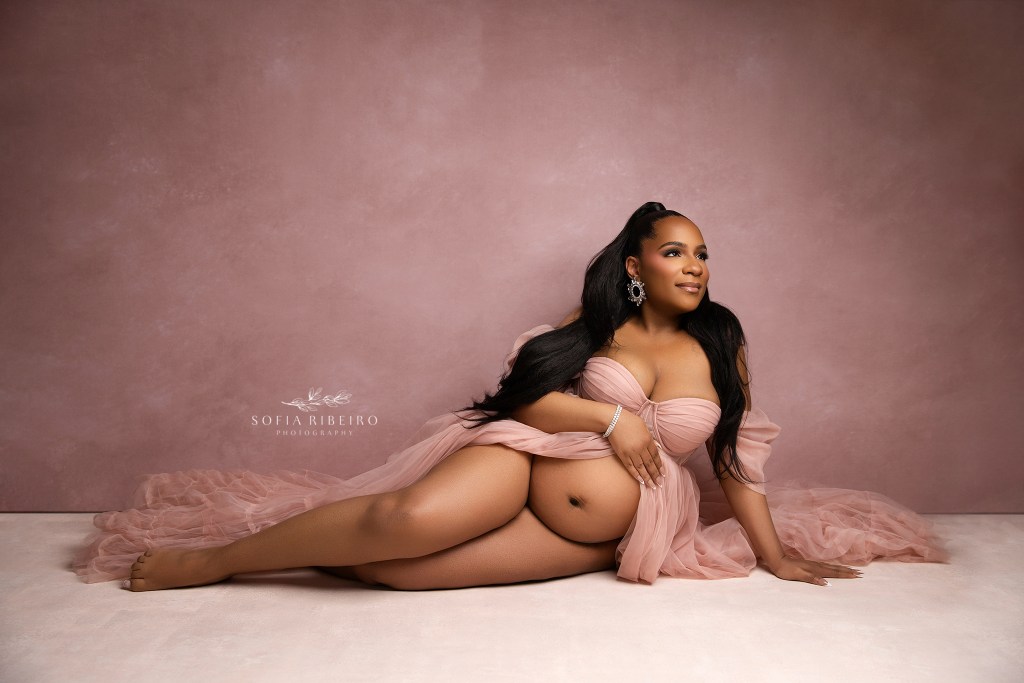 nj maternity photographer captures a mom to be in a soft pink tulle dress against a pink backdrop