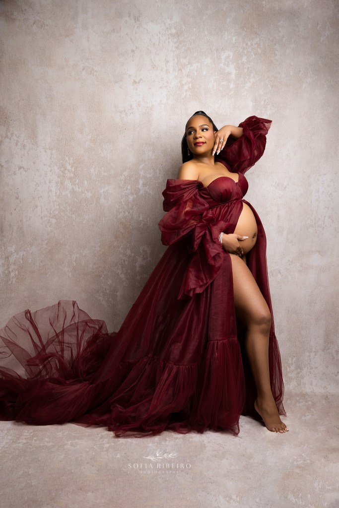 mom to be poses with baby bump exposed in a red dress