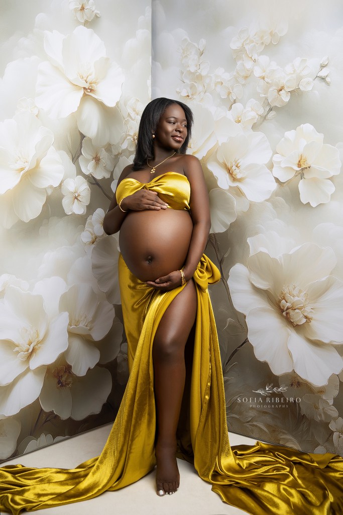 mom to be poses for a nj maternity photographer in golden yellow satin fabric
