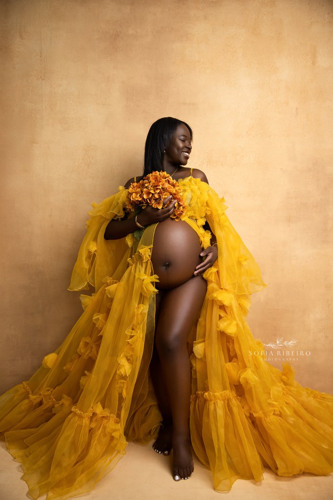 a refined portrait of mom to be cradling her baby bump in a yellow gown