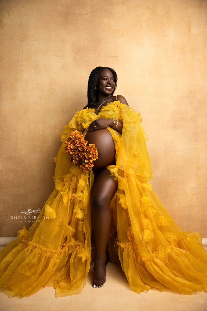 nj maternity photographer captures a radiant smiling mom for maternity portraits against a yellow backdrop
