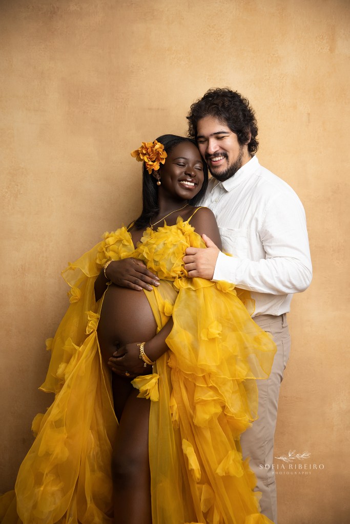 mom and dad share a sweet moment in sunny yellow tones with a handpainted backdrop for maternity photos in nj
