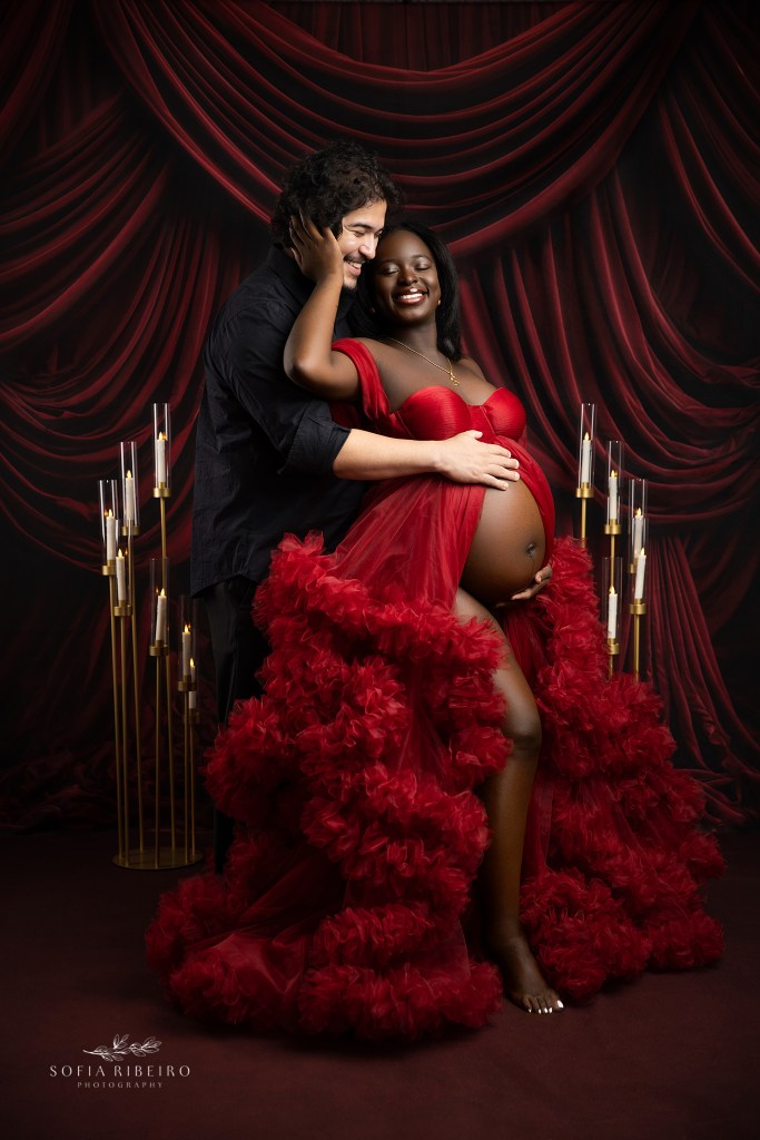 maternity portrait with a couple in bright red and black tones