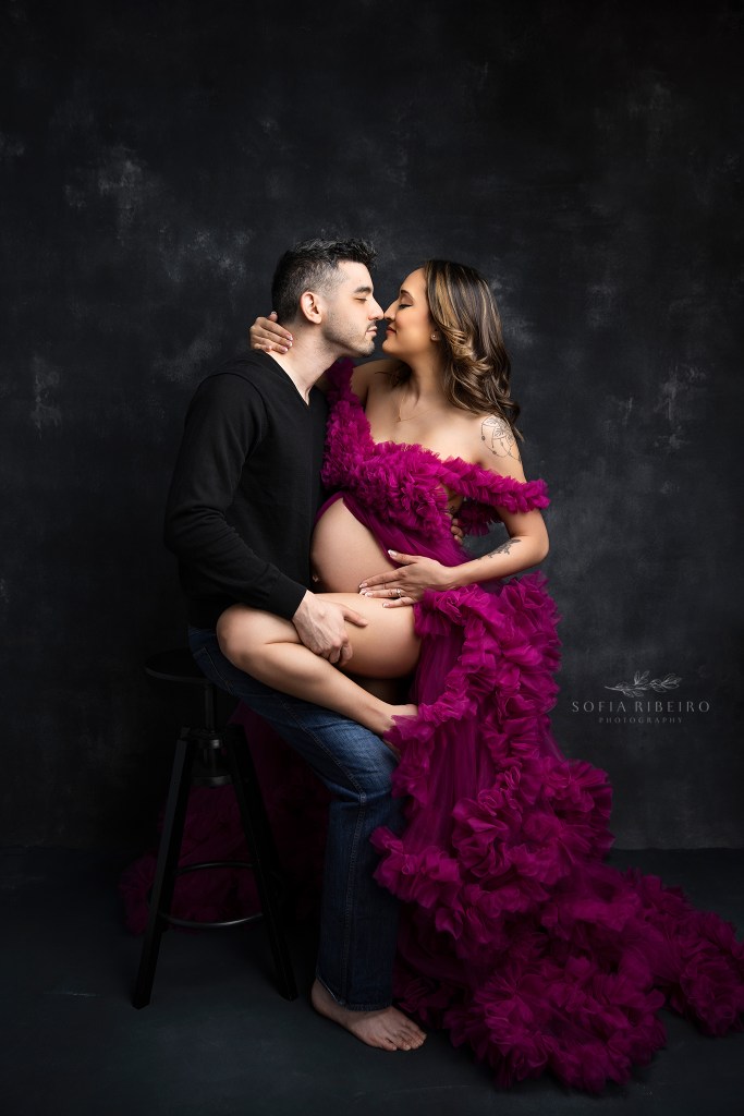 a sensual moment between mom and dad to be in a dramatic set by an nj maternity photographer