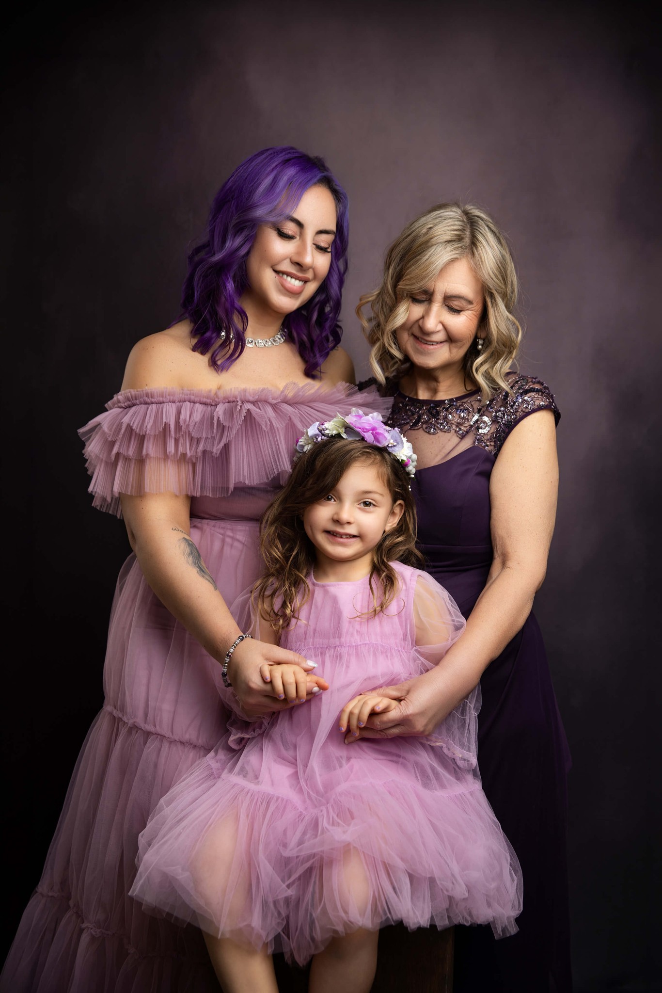 A woman stands with her daughter and grandaughter in matching purple dresses after finding great preschools in mendham ,NJ