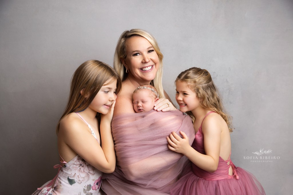 three sisters in moms arms in nj newborn photography studio