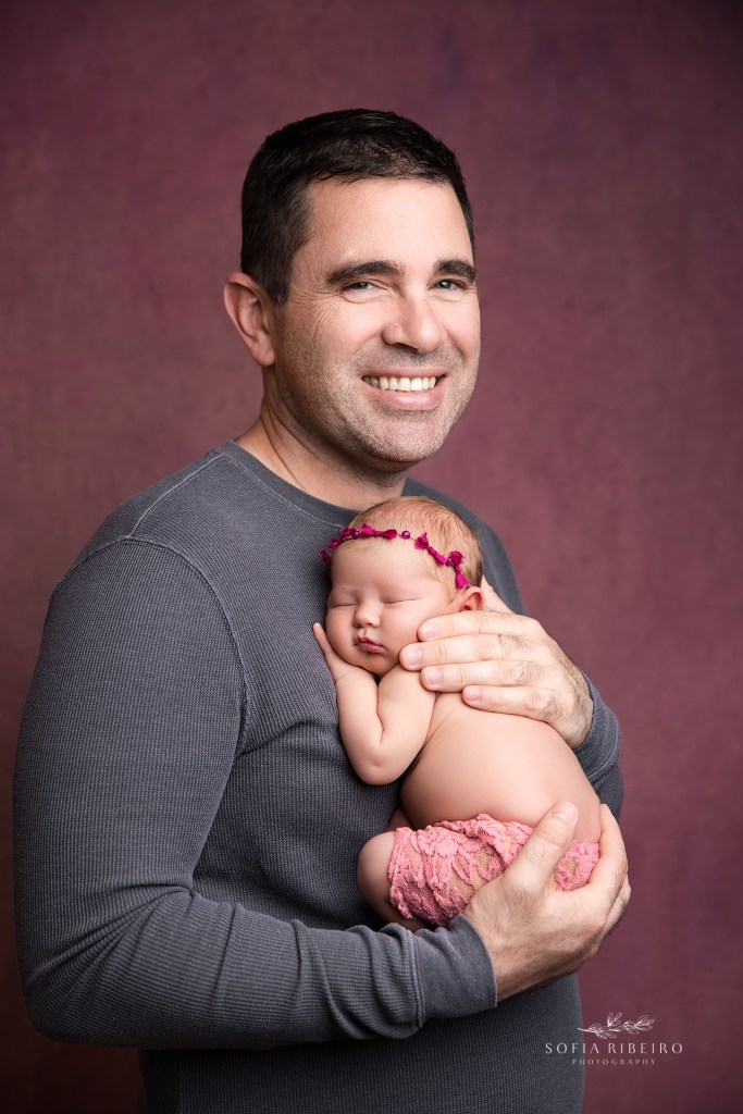dad poses with his newborn daughter