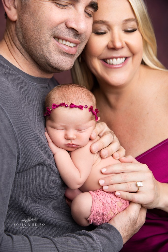 newborn baby girl nestlecd in parents album in nj newborn photography studio in shades of pink