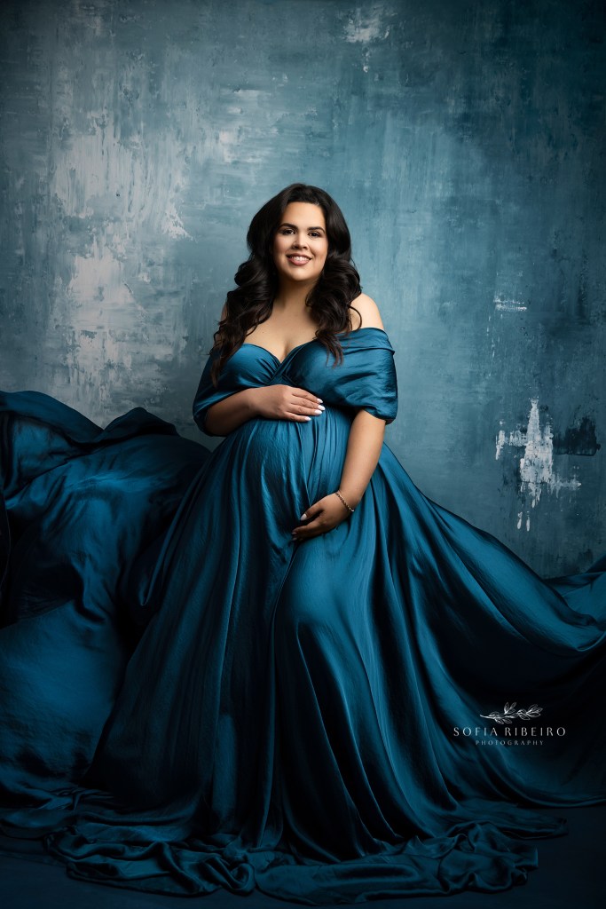 a blue satin flowing gown highlights mom to be's baby bump