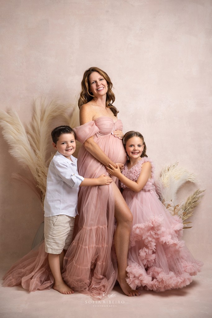 mom to be poses with her two older children for maternity portraits in a nj studio