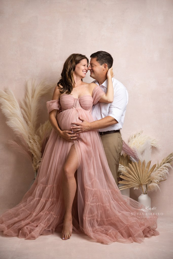 parents to be share a moment in pink cradling the baby bump with an nj maternity photographer