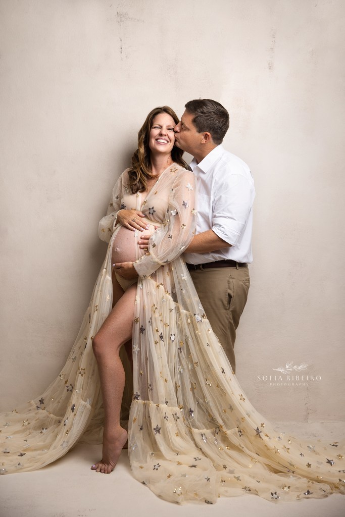 mom to be shares a sweet moment with dad while holding the baby bump during a family maternity session in an nj photography studio