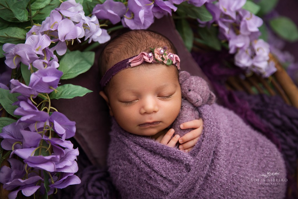 baby girl is wrapped in purple tones and a teddy bear for newborn photos in an nj newborn photo studio