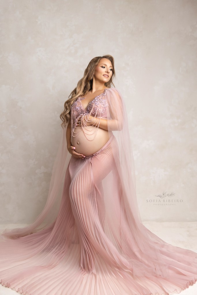 mom to be is draped in soft pink tones during a maternity session in nj