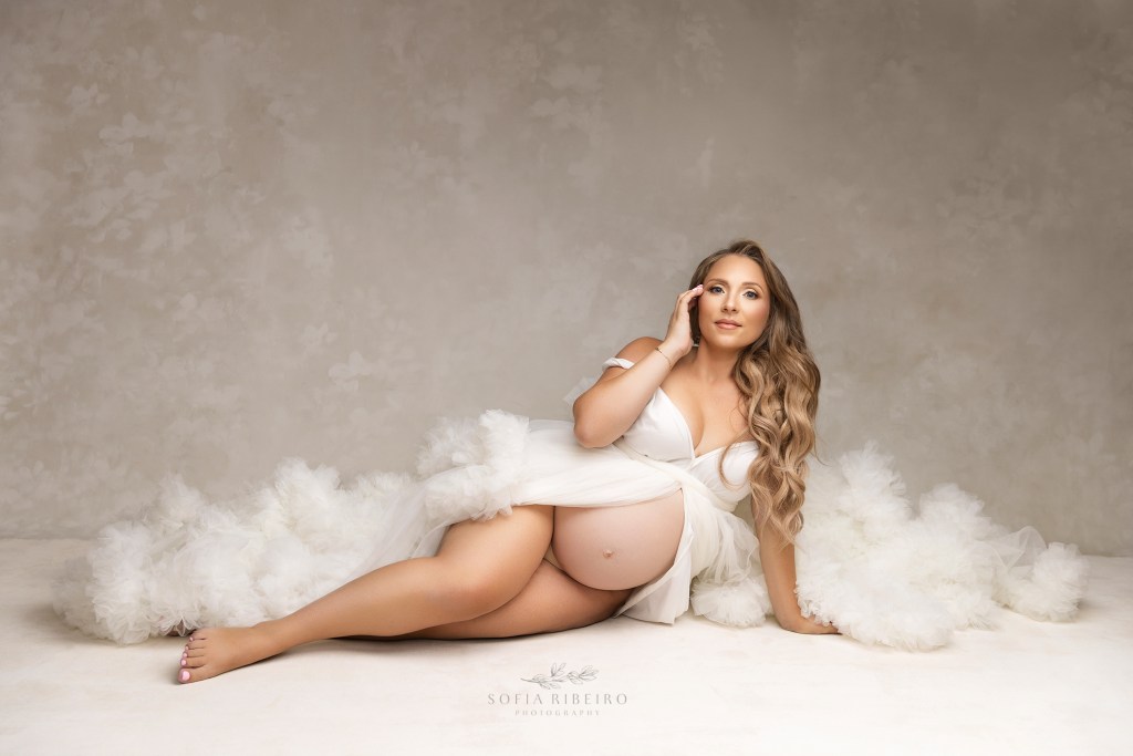 mom to be stuns in a sidelying pose in a white dress for maternity photos in nj
